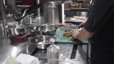 Bir insanın mutfak ortamında yemek tahtasında titizlikle yemek hazırlayışını izleyin. Mutfak becerilerini ve tekniklerini gösterin..