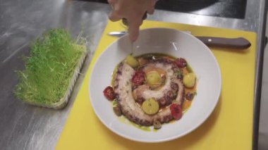 Lokantada ahtapotun son hazırlığı. Tabağa sos ekle.