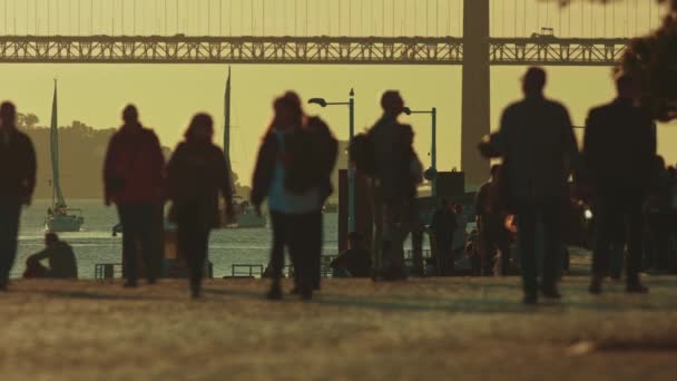Orang Orang Berjalan Sepanjang Pantai Samping Jembatan Pada Jam Emas — Stok Video