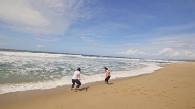 Okyanusla bir kumsalda koşan ve sahilde dalgalarla oynayan iki insan. Aşk konsepti.