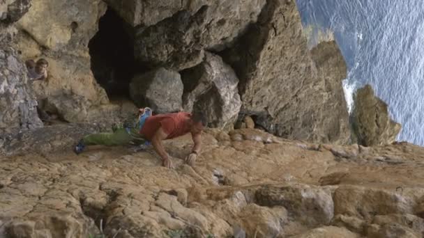Homem Está Subindo Uma Parede Pedra Com Uma Camisa Vermelha — Vídeo de Stock