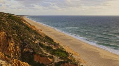 Okyanusa bakan kayalık bir uçurumu olan bir sahil. Kumsal kumlu ve su sakin.