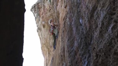 Bir kadın kaya duvarına tırmanıyor. Kadın zorlu arazide yol alırken macera ve heyecan kavramı