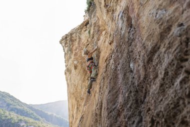 Bir kadın kaya duvarına tırmanıyor. Fotoğraf siyah beyaz.