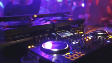 Klavyesi ve iki pikabı olan bir DJ. Manzara enerjik ve canlı.