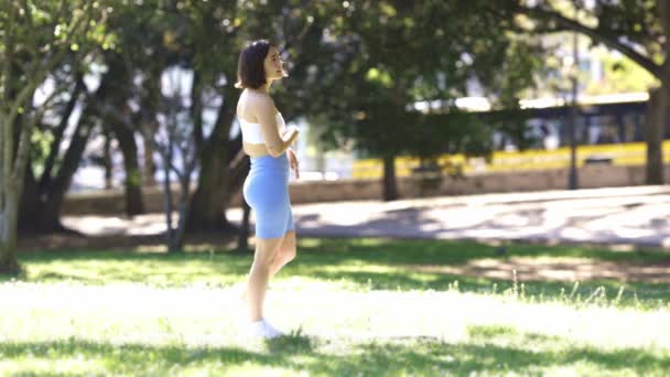 Женщина Гуляет Парке Жёлтым Автобусом Заднем Плане Одета Синий Топ — стоковое видео