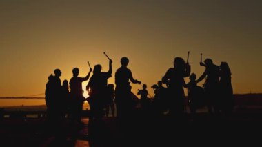 Almada, Portekiz - 9 Mayıs 2024: Bir siluet - bateristler gün batımına karşı çubuklarla müzik çalıyorlar - gezinti güvertesi
