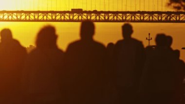 Tagus Nehri 'nin üzerindeki bir köprünün önünde bir araya gelip manzarayı izleyen farklı bireylerden oluşan bir grup..