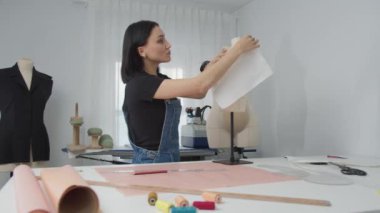 Bir kadın elbise üzerinde çalışıyor, bir parça kumaş kesip dikiyor. Yaratıcılık ve işçilik kavramı, kadın projesi üzerinde dikkatle çalışırken. Makasın varlığı.