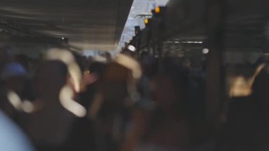 Bir grup insan caddede yürüyorlar. İnsanlar kuyrukta yürüyorlar ve farklı renkte kıyafetler giyiyorlar. Olay yeri bulanık ve insanlar net bir şekilde görünmüyor.