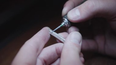 Bir insan bir mücevheri fırçayla parlatıyor. Fırça bir kişinin elinde duruyor.