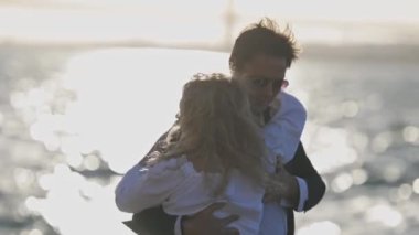 Gün batımında okyanusta dans eden bir çiftin romantik videosu. Güneş arkalarında batıyor, güzel bir mercek patlaması yaratıyor. Romantik videolar, tatil reklamları ve daha fazlası için mükemmel..