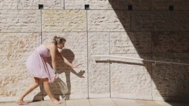 Pembe elbiseli bir kadın, güneşli bir günde parkta dans eder..