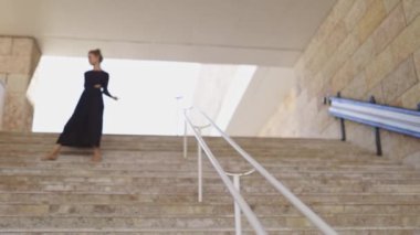 Siyah elbiseli bir kadın merdivenleri çıkıyor, geniş açılı.