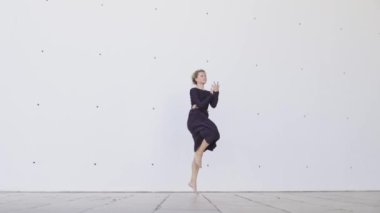 Siyah elbiseli bir kadın sahnede dans ediyor. Kadın hareketleri yoluyla özgürlük ve ifade kavramı
