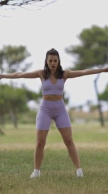 Sportif bir kadının parkta spor dansları vardır. Dikey.
