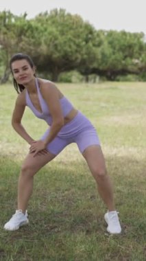 Sportif bir kadının parkta spor dansları vardır. Dikey.