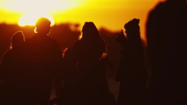 Bir grup insan gün batımına karşı siluetlendi.