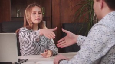 Beyaz gömlekli ve siyah pantolonlu bir adam dizüstü bilgisayar taşırken cep telefonuyla konuşuyor.