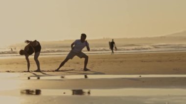 Bir erkek ve bir kadının sahilde dövüş eğitimi var - capoeira - geniş açı