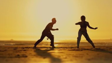 Esnek bir kadının dövüş sanatları eğitimi vardır - gün batımında bir capoeira - yavaş çekim