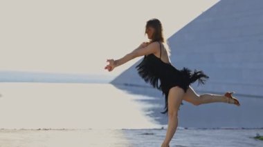 Siyah elbiseli bir kadın binanın önünde dans ediyor. Zarafet ve zarafet kavramı, kadınların hareketleri akıcı ve zariftir. Görüntünün ayarları