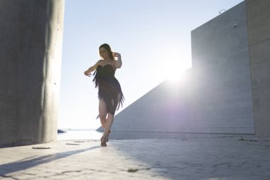 Genç bir kadın şehir ortamında modern bir bale koreografisi yapıyor.