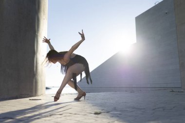 Genç bir kadın modern bir şehir ortamında dışarıda salsa yapıyor.