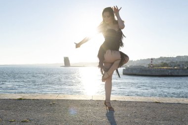 Dansçı gün batımında deniz kenarında koreografi yapıyor.