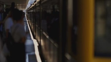 Yavaş çekimde istasyona varan yolcular metroya binmek için sıralarını bekliyorlar.