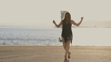 Profesyonel dansçı, deniz kenarındaki beton bir zeminde zarif bir şekilde dans ediyor. Yeteneğini ve zarafetini sergiliyor.