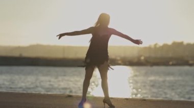 Kadın gün batımında beton bir yüzey üzerinde salsa yapıyor.