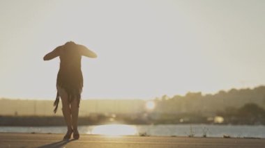 Gün batımında deniz kenarında zarif bir şekilde hareket eden salsa dansçısı.