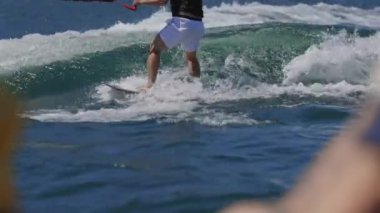 Wakeboardcu, bir tekne tarafından yaratılan bir dalgada sörf yaparken numaralar yapar.