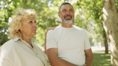 Sevecen yaşlı çift güneşli bir parkta yürürken birbirlerine eşlik etmekten zevk alırlar.