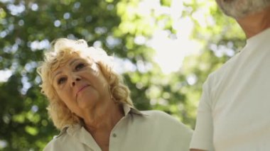 Kıdemli çift birlikte vakit geçiriyorlar, yemyeşil bir parkta sakin bir gezinti yapıyorlar.