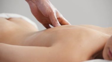 Sarışın, güzel bir kız masaj masasında yatıyor. Masör sırt masajı yapıyor. Tibet Tıbbı