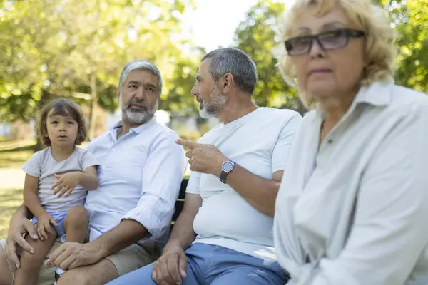 stock image Senior woman is feeling excluded while her family is talking together on a park bench