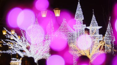 Noel ışıkları pembe bir bokeh efektiyle bulanık bir kale şekli oluşturuyor.