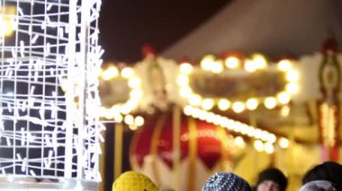 Turistler Noel ruhunun keyfini çıkarıp eski bir atlıkarıncayı seyrediyorlar.