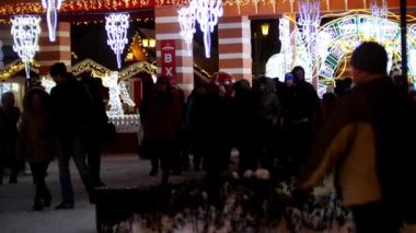 İnsanlar sıcak kış paltolarını giyip gecenin bir yarısı şehrin sokaklarında Noel ışıkları ve süslemelerle dolaşıyorlar.