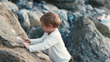 Genç çocuk sahilde güneşli bir günün tadını çıkarırken, merak ve neşeyle dolu.