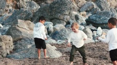 Aile, kayaların arasında enerjik bir şekilde oynayan çocuklarla güzel bir plajda birlikte vakit geçirmeyi seviyor.