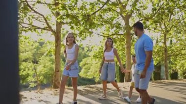 Mutlu aile parkta yürüyor, güneşli günün tadını çıkarıyor.