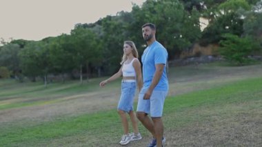 Romantik çift parkta yürürken kadınlar taklalar atıyor.