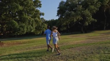 Bir grup arkadaş parkta rahatça yürüyüp koşuyor.