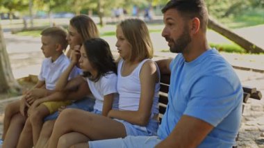 Parkta bir bankta oturan aile sohbete daldı ve birlikte eğlenmeye başladılar.