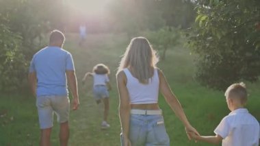 Mutlu bir aile parkta el ele yürüyor.
