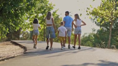 Mutlu bir aile parktaki yolda yürüyor.