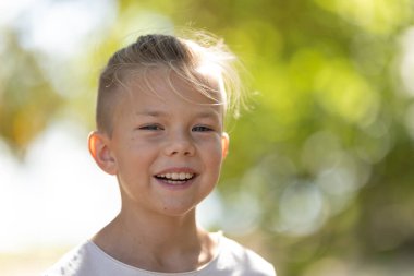 Mutlu çocuk, parlak güneş ışığı altında gülümsüyor.